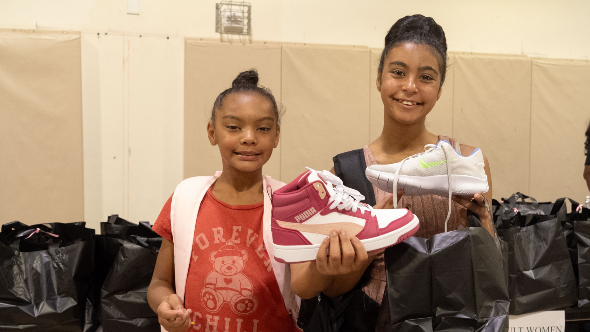 Two kids smiling and holding up new sneakers at the Step Up for DC shoe drive